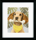 Framed artwork of a dog holding a bone with a yellow bandana against a leafy background
